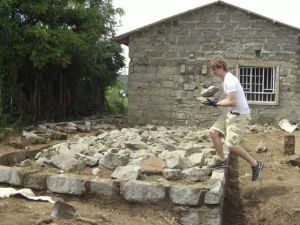Tyler Kerr carries stones to fill the foundation.